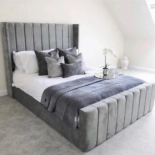 Modern gray upholstered bed with tall headboard, pillows, and textured throw in bright bedroom